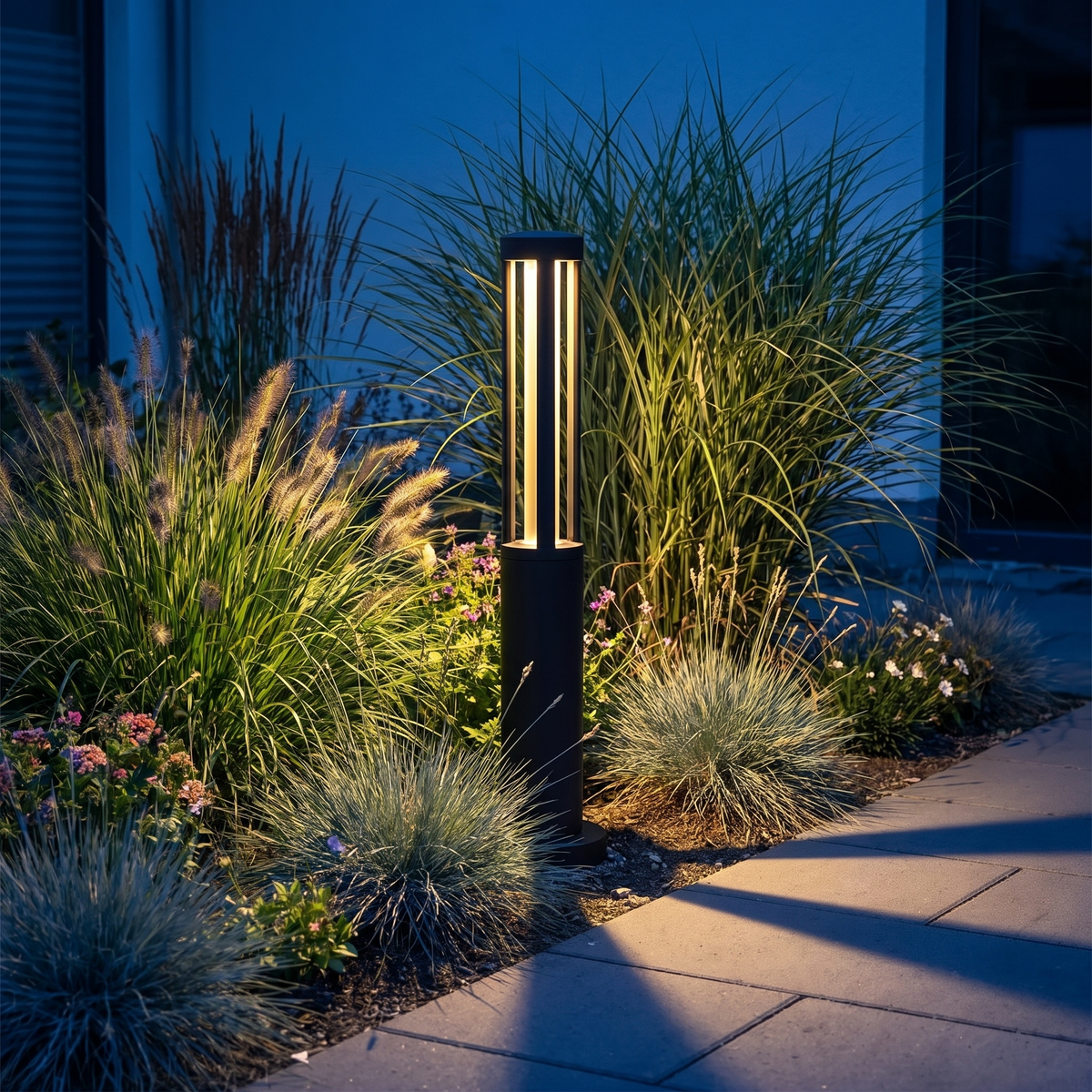 Nordal bollard light among courtyard planting at dusk