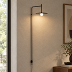 Black swing-arm wall lamp with disc shade close-up on the wall