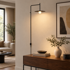 Black swing-arm wall lamp with disc shade on a living room wall