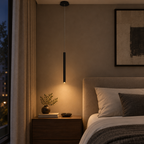 Thin black cylinder LED pendant light beside a bed