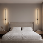 Slate ultra-thin linear LED wall light two of them mounted vertically on each side of an upholstered headboard in a calm hotel-style bedroom with greige walls and crisp white bedding