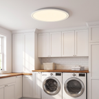 Disc ultra-thin round LED ceiling panel light mounted on the ceiling of a bright modern laundry room with white cabinets