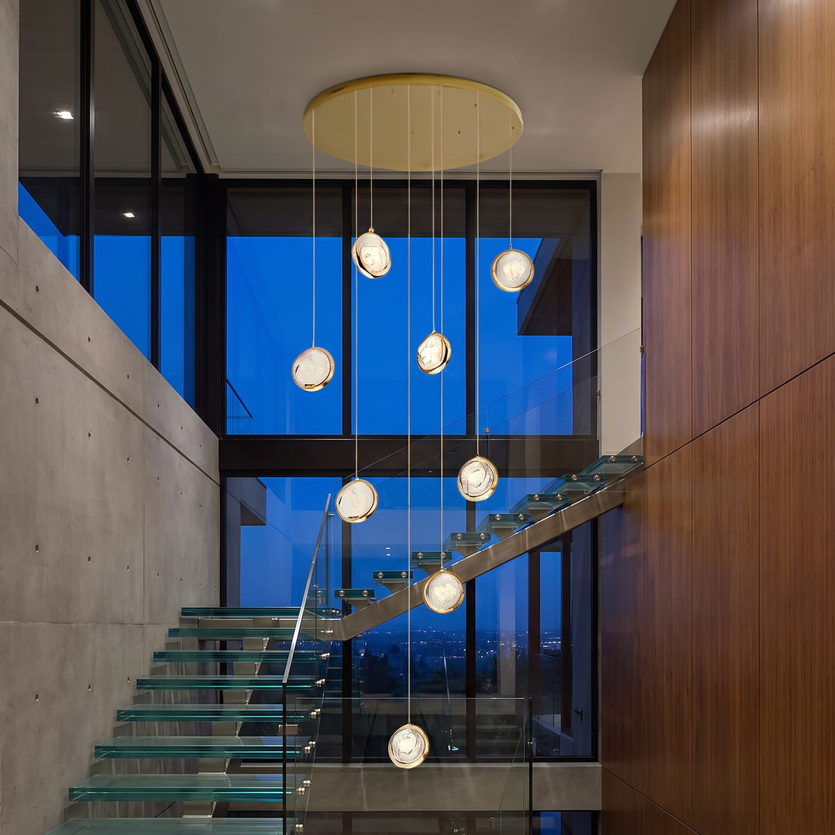 Cascade long crystal globe staircase chandelier hangs down through the tall open stairwell of a luxury modern home with a floating glass staircase