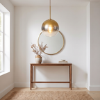 Bulle glass globe pendant light hangs in an entryway above a slim console table with a round mirror