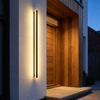 Lumea wall light beside a timber front door at dusk